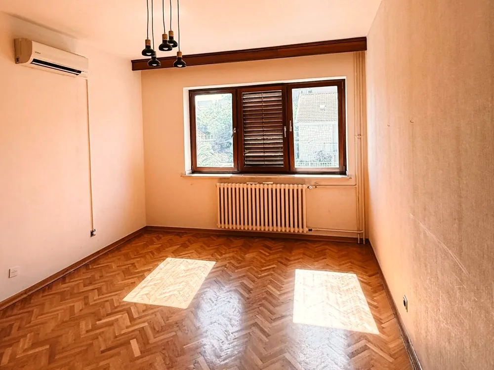 Prazna soba sa parketom riblja kost, sunce pada na pod kroz prozor.